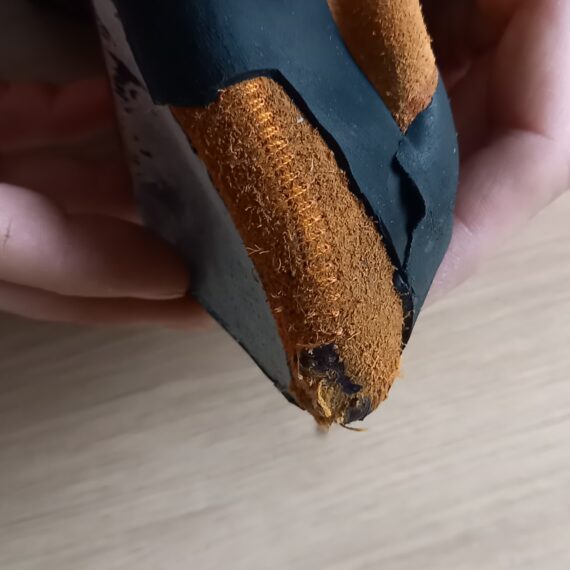 Un chausson d'escalade poncé pour lequel on voit la partie tissu et en dessous l'intercalaire.